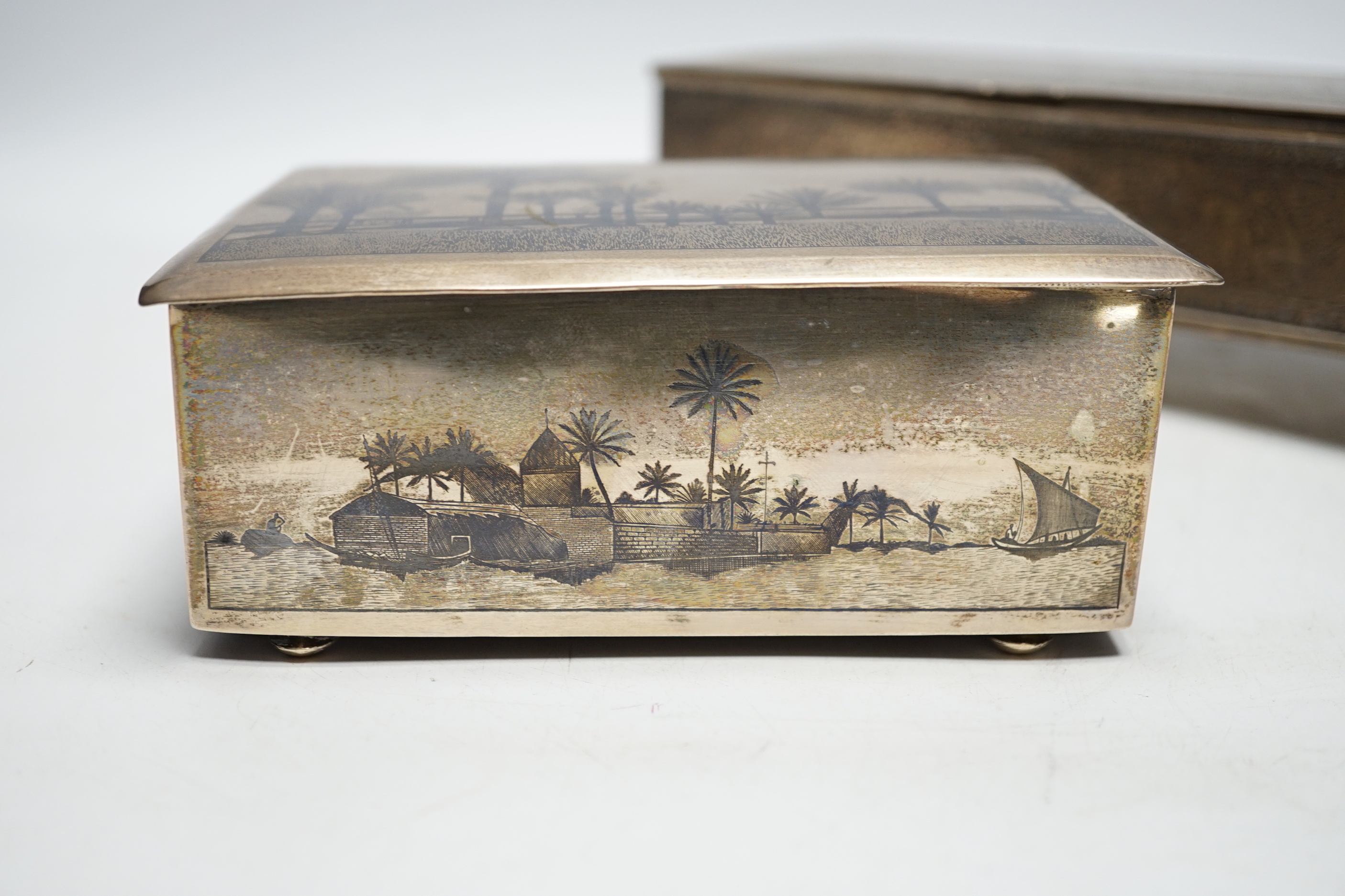 A Persian engraved white metal rectangular cigarette box and a similar white metal and niello cigarette box, largest 20.3cm.